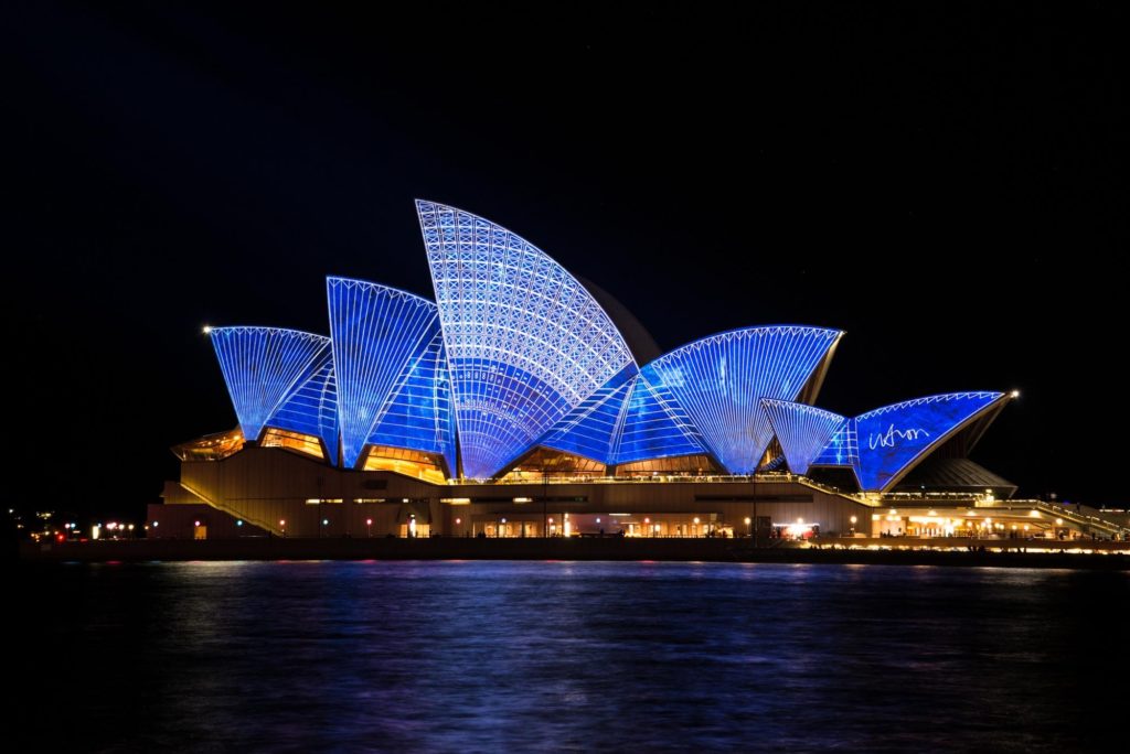 An image of the Sydney Opera House, lit up at night