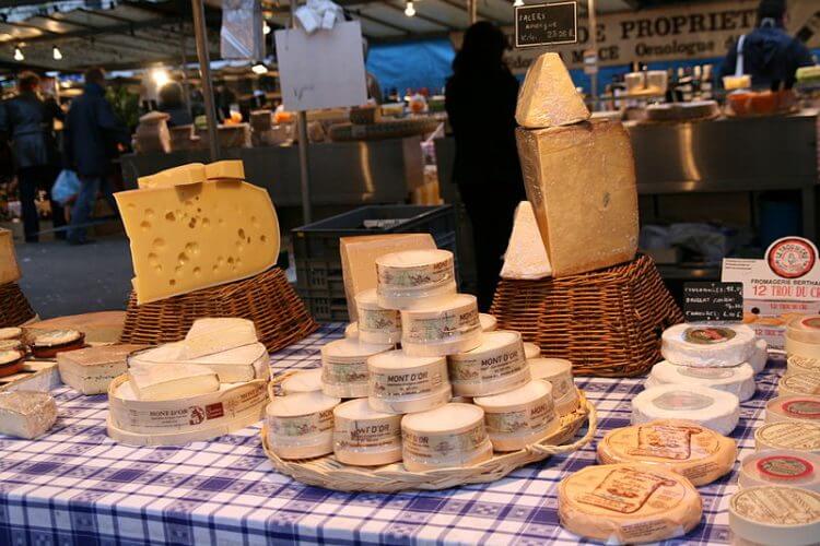 An image of different types of cheese on display at the Marche Bastille in Paris