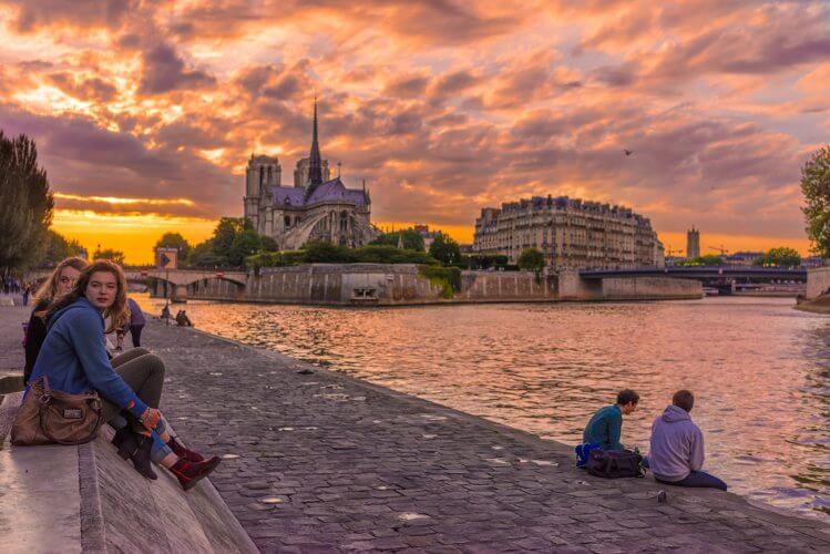 An image of a few people relaxing by on the banks of the Seine