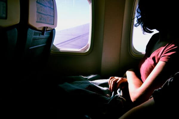 A girl seated in an airplane who is covering herself with a warm blanket is pictured here
