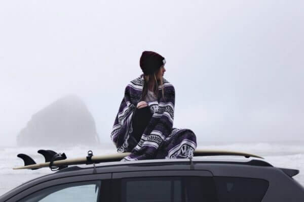 A picture of a girl using one of the best travel blankets to keep herself warm