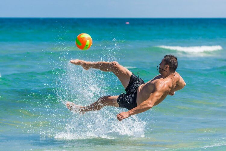 A man playing with a volleyball in the water