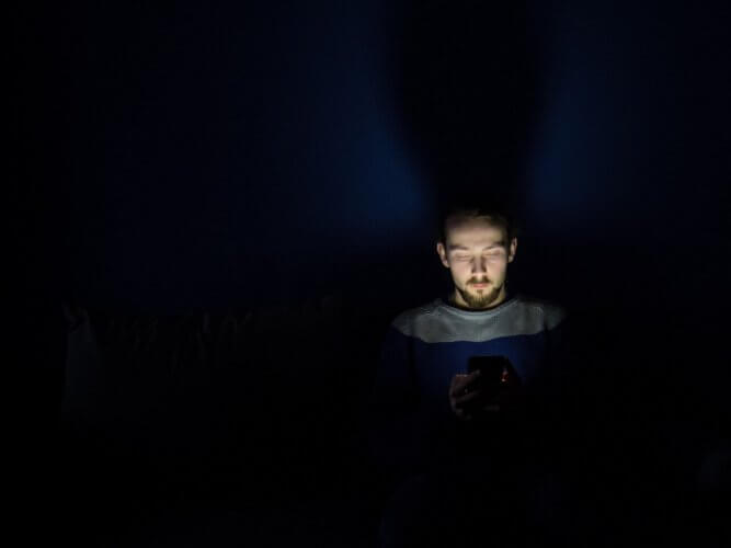 A man using his phone in the dark