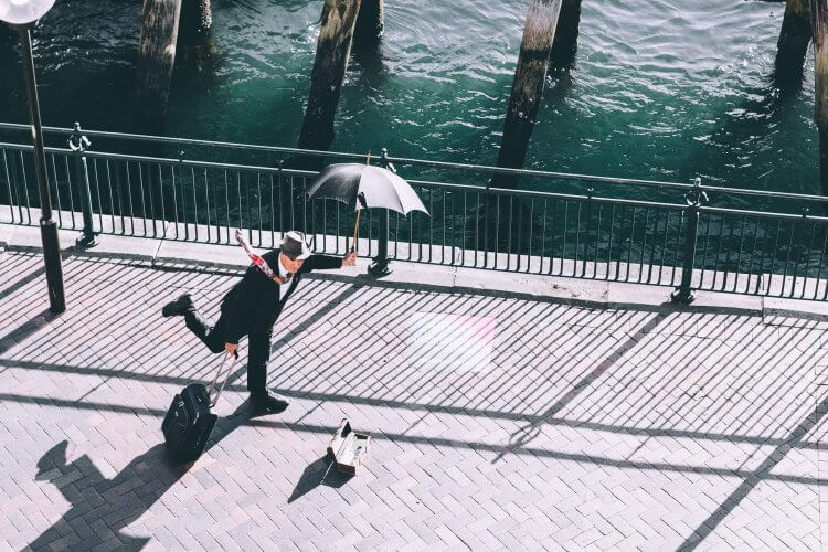 A picture of a man traveling with an umbrella in the heat