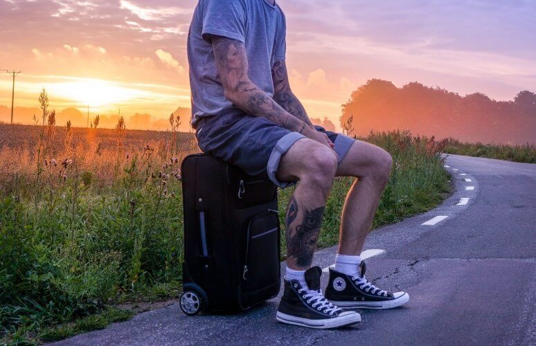 An image of a man sitting on a roller-board checked luggage