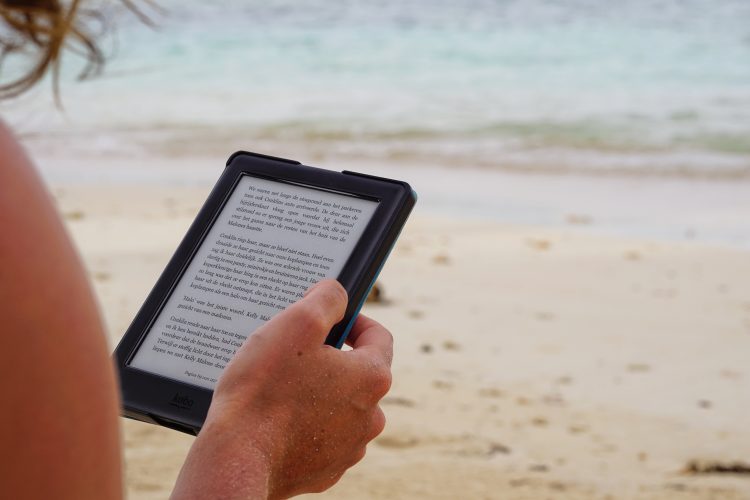 Woman reading e-reader on the beach