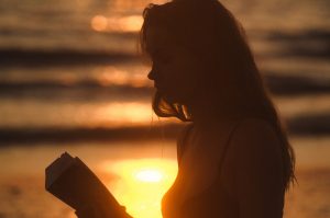 Woman reading on the beach at sunset