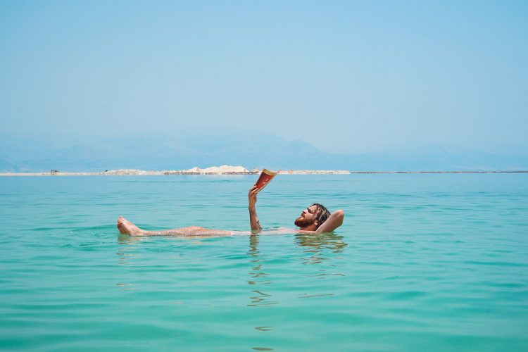 Man reading a book whilst floating in the sea