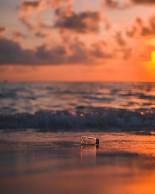 Plastic bottle in the sea at sunset