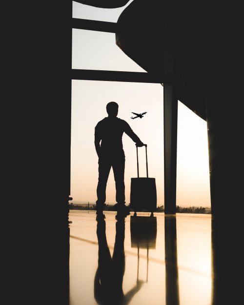 Man standing by airport window with suitcase